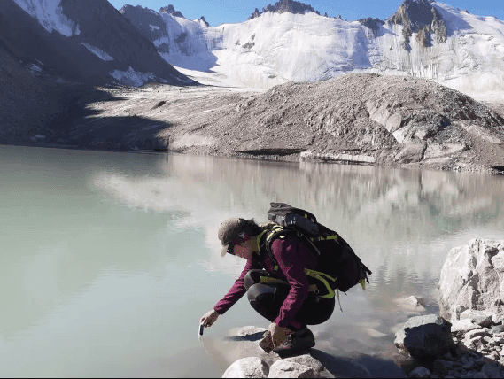 Person sampling water from a glacial lake